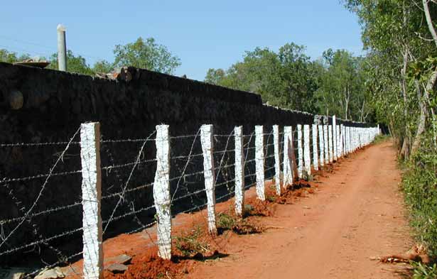 ... surrounded by a high, barbed wire covered compound wall..