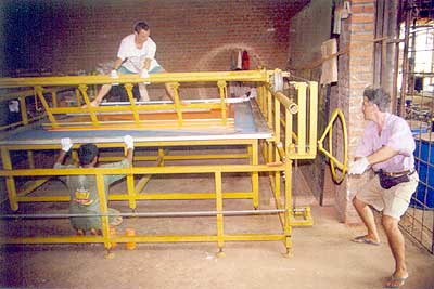 Moment of precision: as the upper frame is evenly moved over the glass beneath the silkscreen, the paint is squeezed down through the screen onto the glass